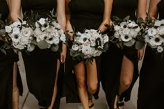 bridesmaids in black dresses holding bouquets with white flowers and greenery on them