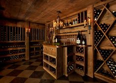 a wine cellar filled with lots of bottles and glasses on top of wooden shelves next to a checkered floor