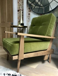 a green chair sitting in front of a clock on a wooden floor next to a white rug