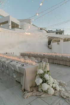 a long table is set up with white flowers and candles for an elegant dinner party