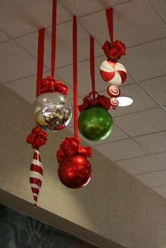 christmas ornaments hanging from the ceiling in an office cubicle decorated with red and green ribbons