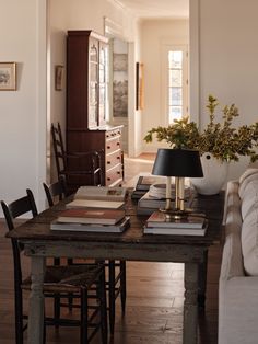 a table with books and a lamp on it in a room that has white walls