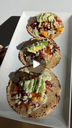 three tortillas on a white plate topped with guacamole and salsa