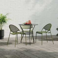 an outdoor table and chairs with plants in the corner next to it on a wooden floor