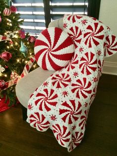 a red and white blanket sitting on top of a chair next to a christmas tree