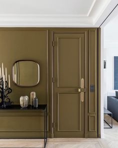 a living room with green walls and a mirror on the wall next to a bench