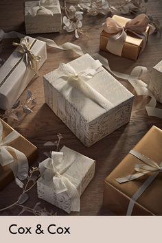 several wrapped gift boxes on a table with ribbons and bows all around the box,