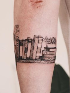 a person with a tattoo on their arm that has books and plants on it,