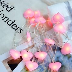 pink heart shaped string lights are on the table next to an envelope with a photo