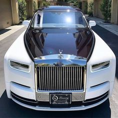 the front end of a white rolls royce parked in a driveway next to a house