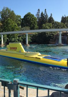 a yellow submarine floating on top of a body of water next to a metal fence