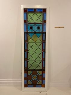 a stained glass door in the corner of a room with white walls and flooring