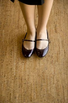 a woman's legs wearing brown shoes on top of a wooden floor