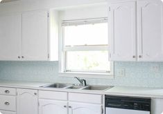 a kitchen with white cabinets and blue wallpaper on the backsplash is shown