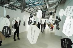 people are standing in an art gallery with black and white signs hanging from the ceiling