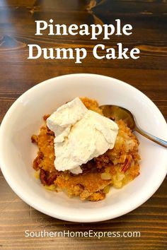 pineapple dump cake with whipped cream in a white bowl on top of a wooden table