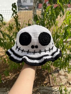 someone is holding up a crocheted hat that looks like a skull with black eyes