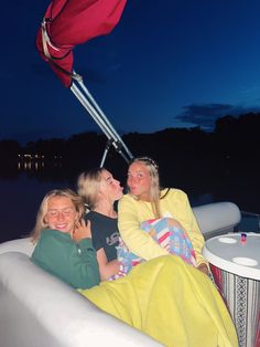 three women are sitting on the back of a boat