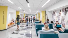 people are sitting in chairs and walking through an office lobby with yellow walls, black and white checkered floor