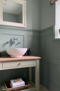 a white sink sitting under a bathroom mirror next to a wooden shelf with towels on it