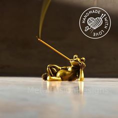 a gold colored figurine is laying on the floor with a stick in it's mouth