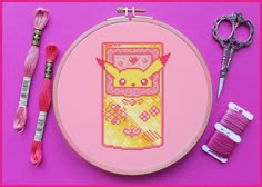 a cross stitch project with scissors, thread and spools on a purple background