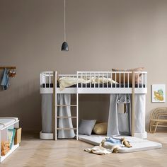 a white bunk bed sitting on top of a wooden floor next to a baby crib