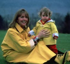 a woman sitting on the ground with a child in her lap, both wearing yellow raincoats