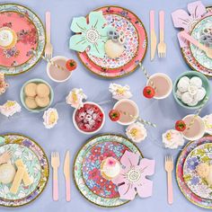 the table is set with colorful plates and flowers