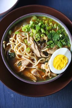 a bowl filled with noodles, meat and an egg sitting on top of a table