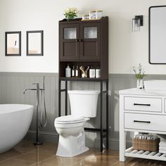 a white toilet sitting next to a bath tub under a bathroom mirror on top of a wooden cabinet