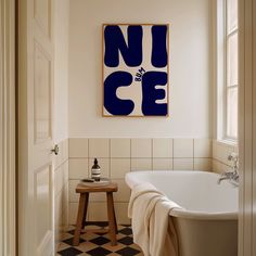 a white bath tub sitting next to a wooden stool under a painting on the wall