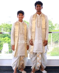 two young men dressed in white standing next to each other on a window sill