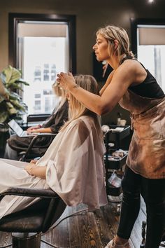 a woman is getting her hair cut by another woman in a salon with other people