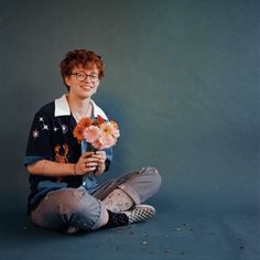 a woman sitting on the floor holding flowers