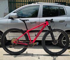 a red bike parked next to a silver car