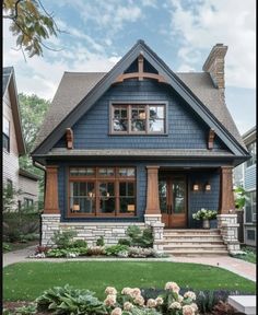 a blue house with brown trim and wood accents on the front door, windows, and steps