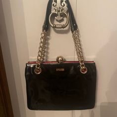 This Beautiful Kate Spade Shoulder Bag Is A Must-Have For Any Fashion-Forward Woman. The Bag Features A Sleek Black Patent Leather Exterior With Gold-Plated Hardware, And A Red Leather Lining. The Bag Has Double Handles And A Clasp Closure, Making It Easy To Carry Around All Day. Measuring 11 Inches In Width, 8 Inches In Height And Depth, This Medium-Sized Bag Is Perfect For Carrying All Your Daily Essentials. The Bag Is Part Of The Kate Spade The Journal Product Line, And Its Solid Pattern And Kate Spade Shoulder Bag, Medium Sized Bags, Black Handbag, The Journal, Daily Essentials, Kate Spade Bag, Solid Pattern, Black Patent Leather, Black Handbags