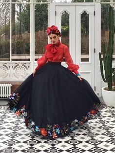 a woman in a red top and black skirt with flowers on her head is posing for the camera