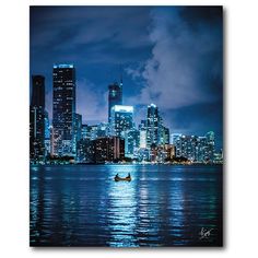 a boat floating on top of a body of water in front of a city at night