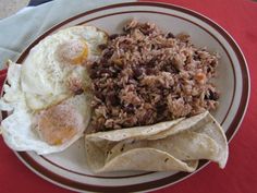 a plate with rice, beans and an egg on it next to tortillas