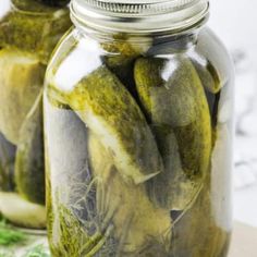 two jars filled with pickles sitting on top of a table