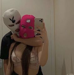 a woman taking a selfie in front of a mirror with two masks on her head