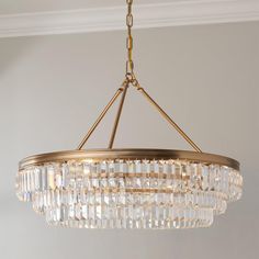 a chandelier hanging from the ceiling in a room with white walls and gold fixtures