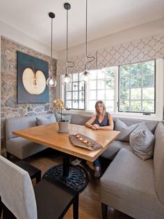 a woman sitting at a wooden table in front of a gray couch and two chairs