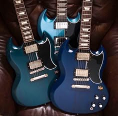 two electric guitars sitting side by side on a couch