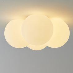 three round lights are hanging from the ceiling in a room with gray walls and flooring