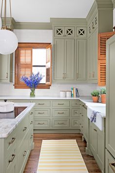 a kitchen filled with lots of green cabinets and white counter tops next to a window