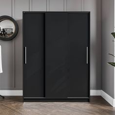 a black cabinet in a room with a mirror on the wall and a chair next to it