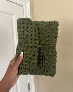 a hand holding up a green crochet purse